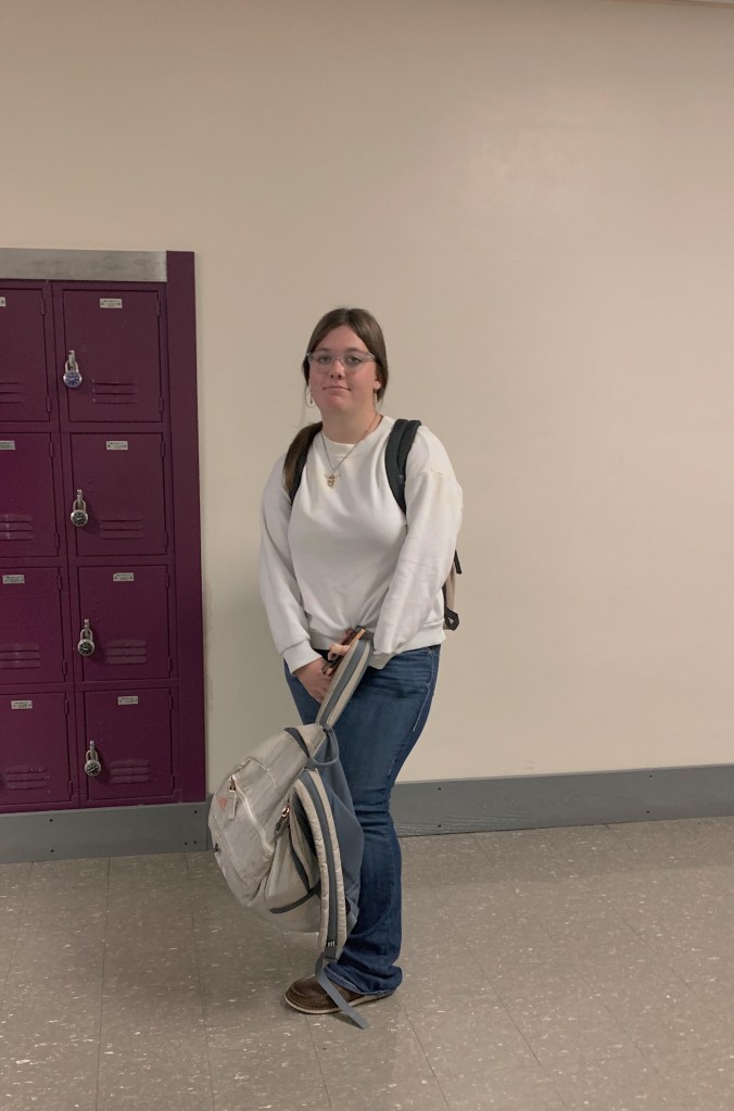 A OHS Student stopping to pose for a picture by holding her bookbag and standing still.