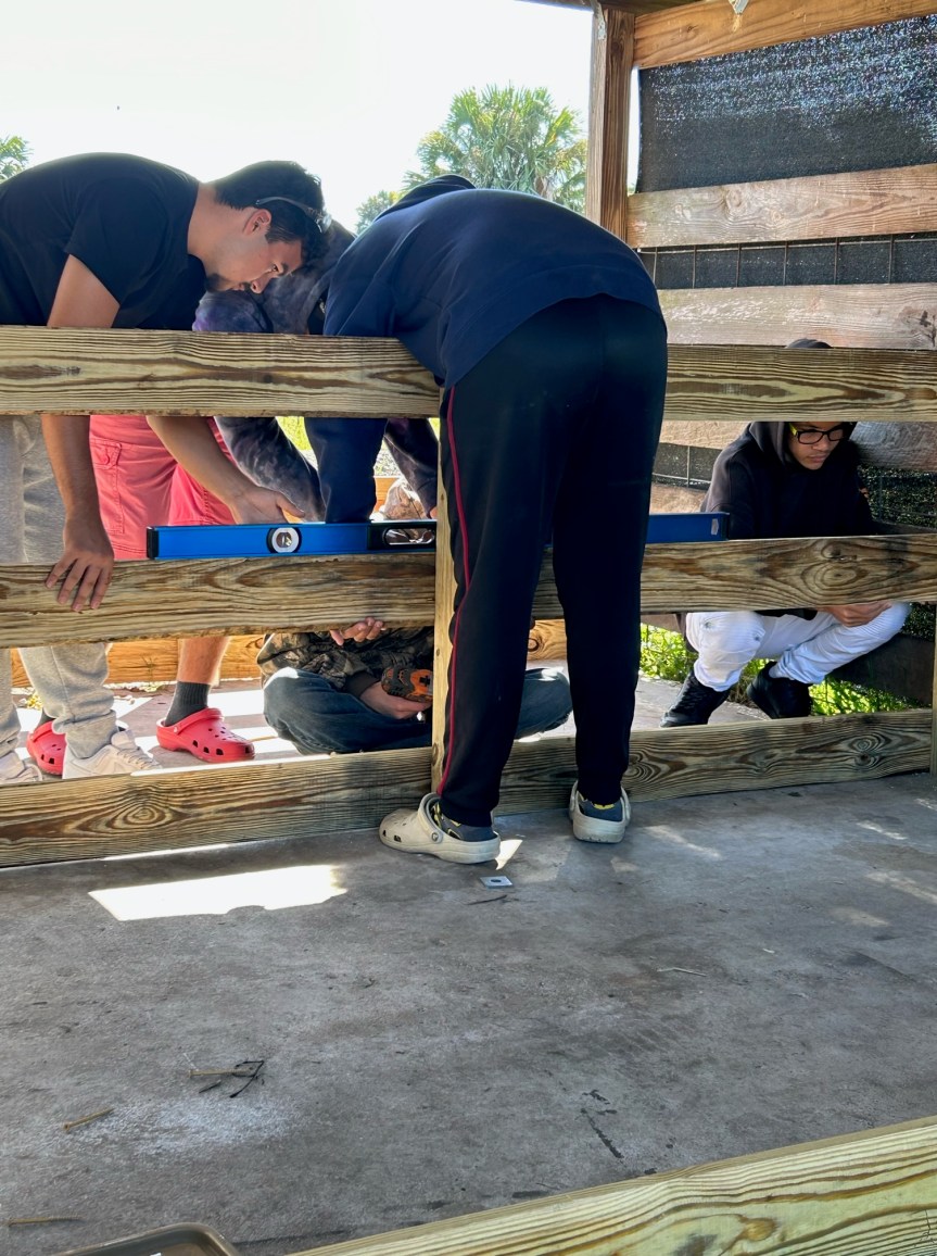 Several students are drilling things into wood palettes