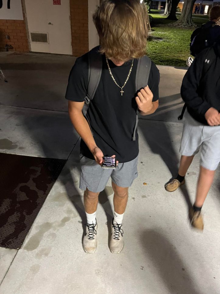 a downward angle picture of Bradly Philips taking out his phone, to play his music.