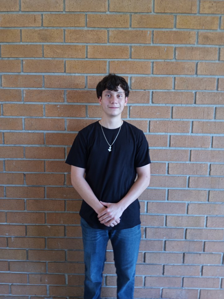 A standing front body picture of Daniel Gil with his hands held in front of him. He is smiling with no teeth and looking at the camera.