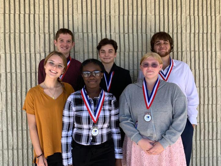 Debate students lined up with their medals around their necks.